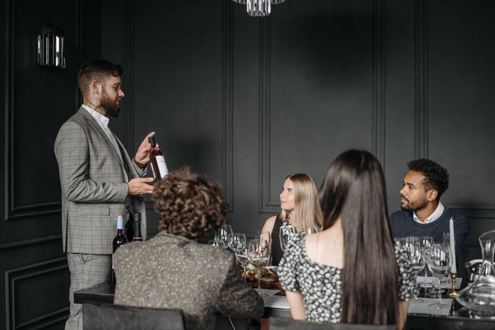 Sommelier presentando una copa de vino a un grupo en una cata