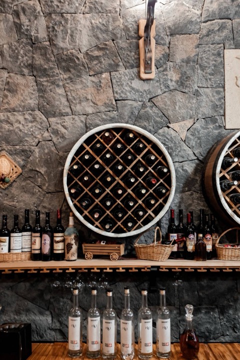 Estante circular de botellas de vino contra una pared de piedra